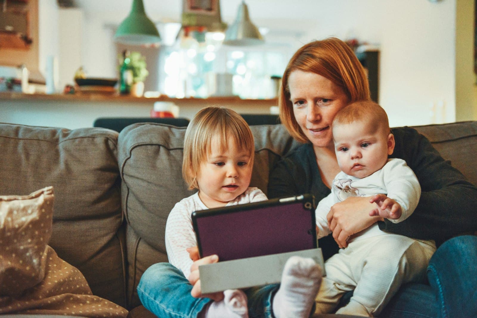 Mãe com duas crianças pequenas acompanhando o portal da família em um tablet
